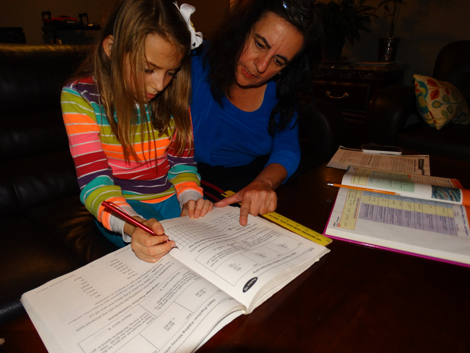 Anna helping an elementary student with a math workbook